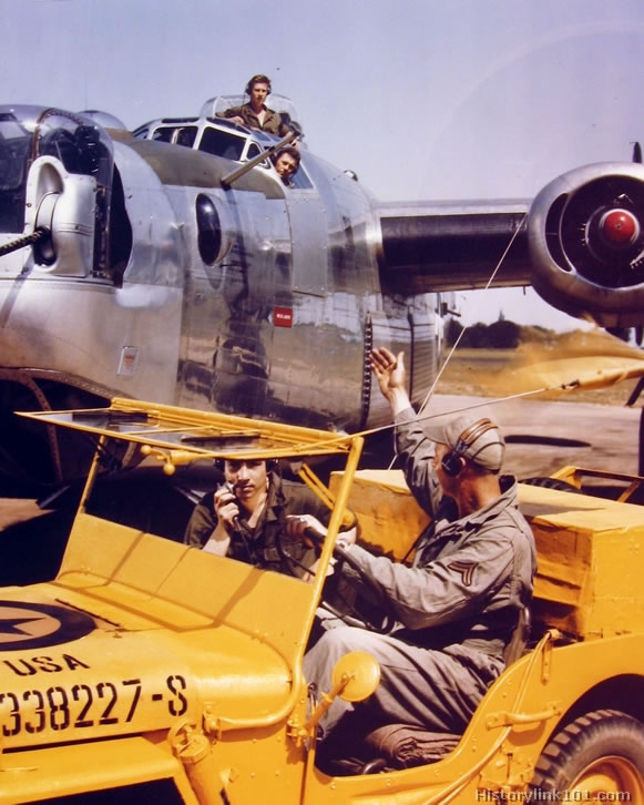 Control jeep occupants direct a Consolidated B-24 to the runway for take-off at a base in Engl...jpg
